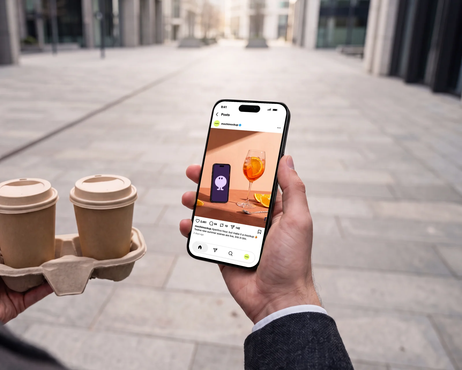 iPhone held in a city street next to two takeaway coffees, showing an Instagram post by mochimockup: a phone and an Aperol spritz on a terracotta table