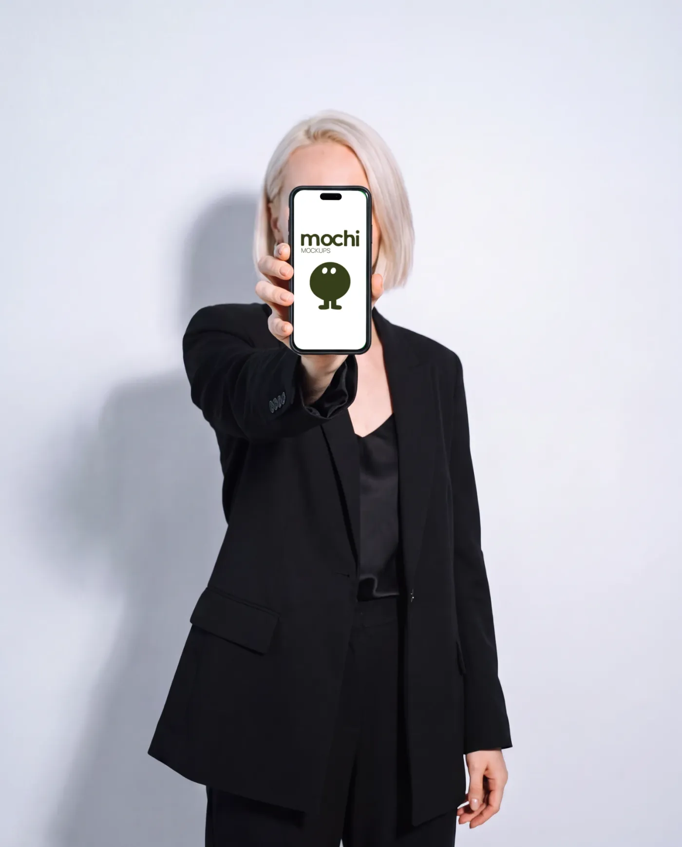 Phone mockup held in hand, studio scene — Black Suit White Wall Handheld